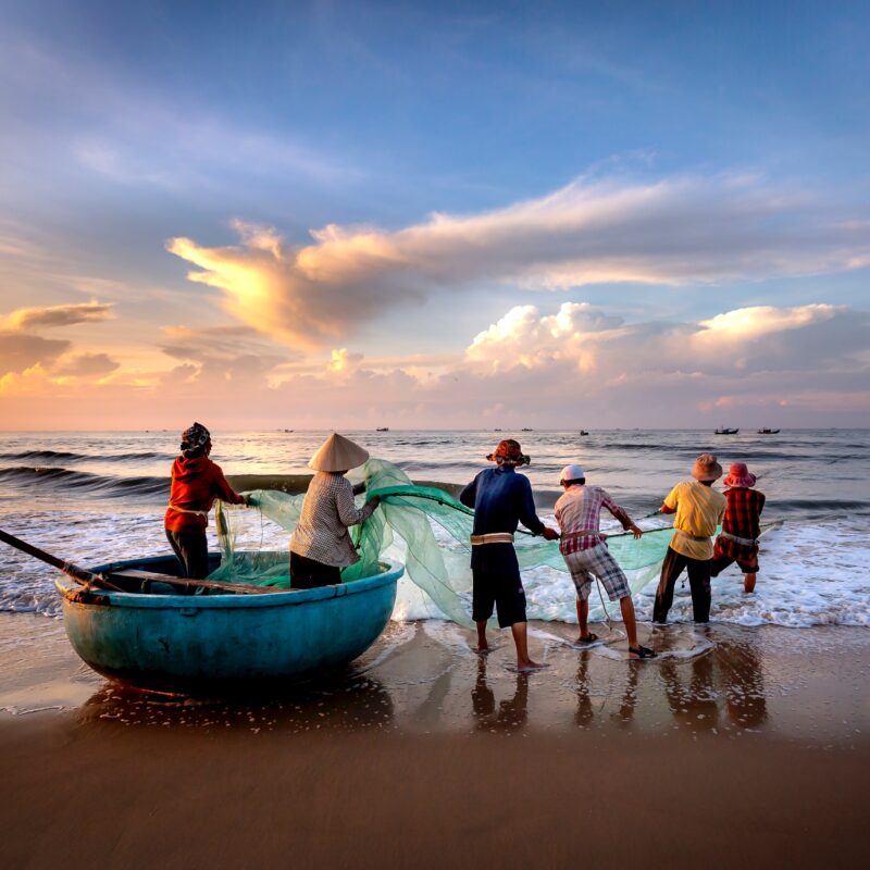 Group of fisherfolk pulling net out of the water.