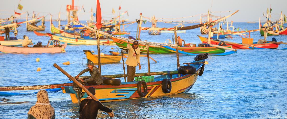 Asian fisherman on colorful handcrafted Balinese fishing boat.