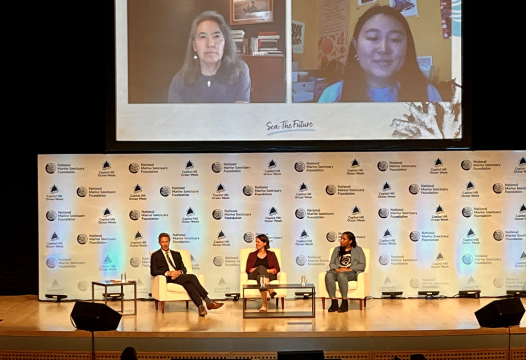 Image of panel with three seated in-person speakers and two virtual speakers.
