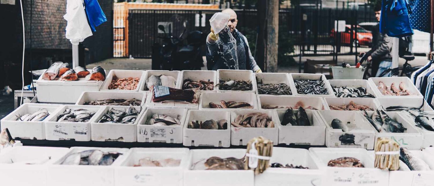 Man stands behind counter of a fish market.